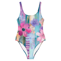 Colorful one-piece swimsuit featuring aqua blue, pink, lavender, and pastel floral watercolor print for beach and resort wear
