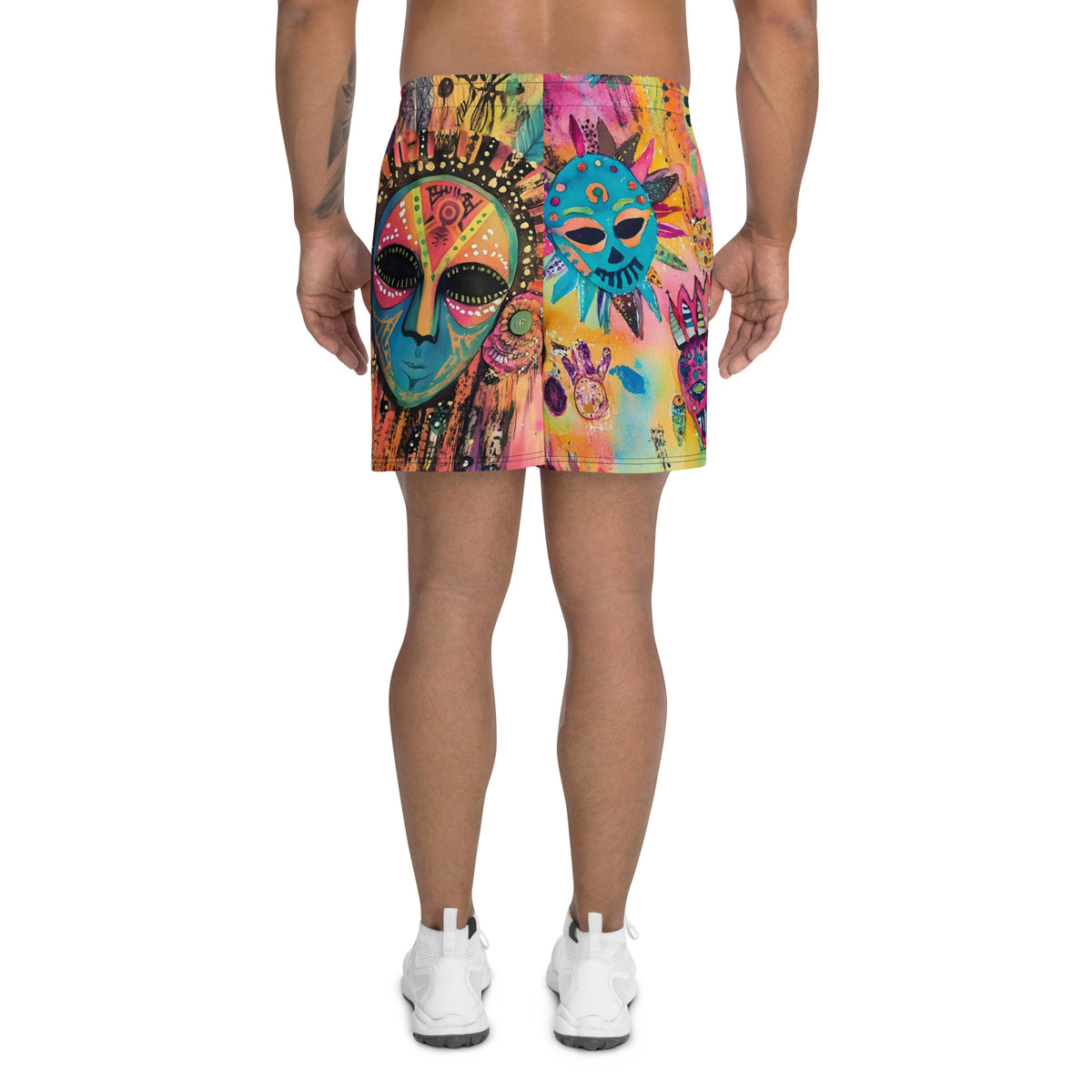 Long sports shorts featuring a vibrant psychedelic tribal mask print with expressive painted faces, decorative folk-art symbols, abstract shapes, brushstrokes, and colorful collage-like textures in turquoise, teal, coral, pink, magenta, orange, yellow, purple, black, and earthy tones. Unisex athletic design with a longer cut, elastic waistband, and bold artistic all-over pattern