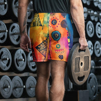 Aztec-inspired long sports shorts featuring a colorful tribal geometric abstract print with triangles, sun-like symbols, dots, decorative linework, and organic motifs in yellow, orange, coral, pink, magenta, purple, turquoise, teal, and navy. Long athletic cut with elastic waistband and white drawstring