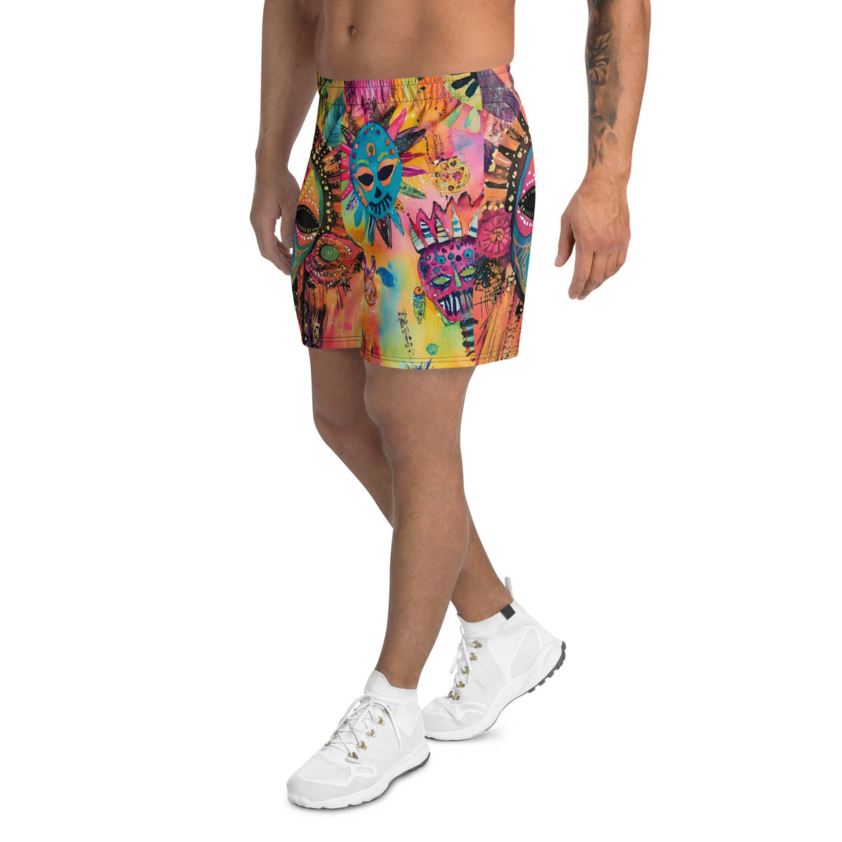 Long sports shorts featuring a vibrant psychedelic tribal mask print with expressive painted faces, decorative folk-art symbols, abstract shapes, brushstrokes, and colorful collage-like textures in turquoise, teal, coral, pink, magenta, orange, yellow, purple, black, and earthy tones. Unisex athletic design with a longer cut, elastic waistband, and bold artistic all-over pattern