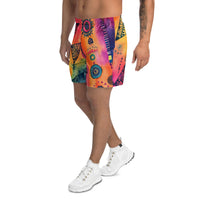 Aztec-inspired long sports shorts featuring a colorful tribal geometric abstract print with triangles, sun-like symbols, dots, decorative linework, and organic motifs in yellow, orange, coral, pink, magenta, purple, turquoise, teal, and navy. Long athletic cut with elastic waistband and white drawstring