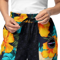 Vibrant Rebel tropical floral wide-leg joggers with all-over hibiscus and palm leaf print in orange, yellow, and teal on dark background